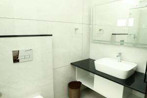 a white bathroom with a sink and a mirror at Aamys Home in Kalpetta