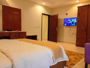 a bedroom with a bed and a flat screen tv at شقق ليالي الشاطئ in Al Qunfudhah