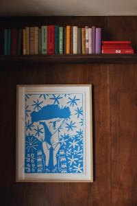 a framed picture on a shelf with books at Hôtel Le Voltaire in Arles