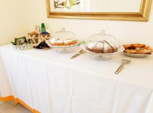 a table with two cakes and pastries in glass domes at Andasì in Pachino +14 photos
