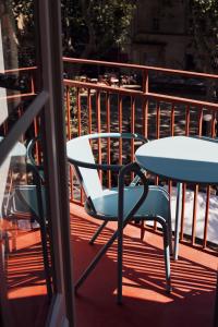 two tables and a chair on a balcony at Hôtel Le Voltaire in Arles +3 photos