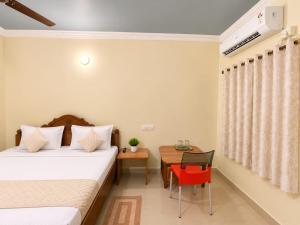 a bedroom with two beds and a table with a red chair at Hotel Oceano in Puri
