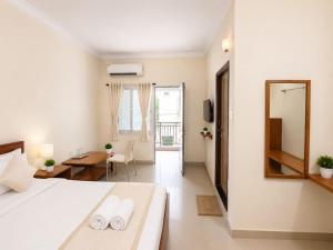 a white bedroom with a bed and a mirror at Hotel Oceano in Puri