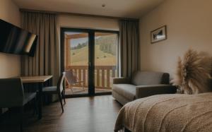 a hotel room with a bed and a chair and a desk at Rössl Lodge in Gerlos