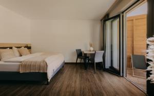a bedroom with a bed and a table with chairs at Rössl Lodge in Gerlos
