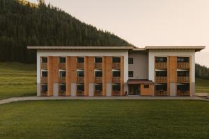 a large building with a grass field in front of it at Rössl Lodge in Gerlos