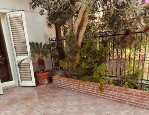 a porch with a fence with plants and a tree at Ciuscia 0 in Calatabiano