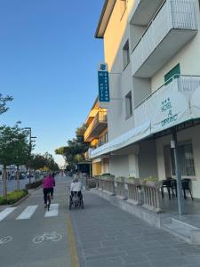 Zwei Personen fahren mit Fahrrädern eine Straße entlang neben einem Gebäude in der Unterkunft Hotel Al Capitano in Caorle
