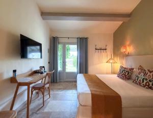 a hotel room with a bed and a desk and a television at Hotel Mas Des Barres in Saintes-Maries-de-la-Mer