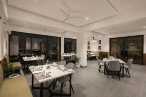a dining room with tables and chairs and windows at Rosastays Kutch in Tuna