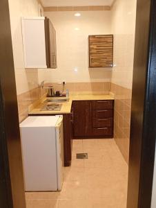 a small kitchen with a white refrigerator and cabinets at شقق ليالي الشاطئ in Al Qunfudhah