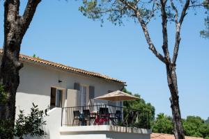 a house with a balcony with chairs and an umbrella at Sélection Camping La Croix -Valmer in La Croix-Valmer