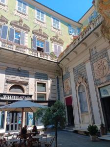 people sitting under an umbrella in front of a building at Splendido Bilocale in Savona