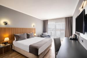 a hotel room with a bed and a tv at Odelia Resort Hotel in Kuşadası