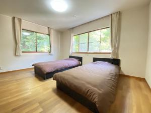a bedroom with two beds and two windows at トラストメゾン西伊豆 in Ukusu