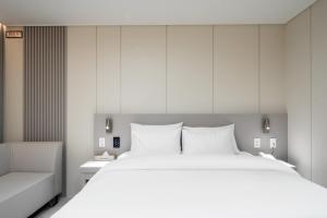 a bedroom with a large white bed and a couch at 제니스 호텔 in Jecheon +38 photos