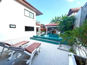 a patio with two lounge chairs and a swimming pool at Big leaf villa kohsamui in Bangrak Beach