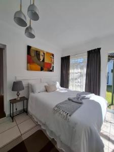 a white bedroom with a large bed and a window at Mahem Guest House in Memel