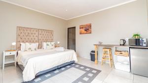 a bedroom with a large bed and a kitchen at Bosveld In Die Stad 2 Guesthouse in Alberton