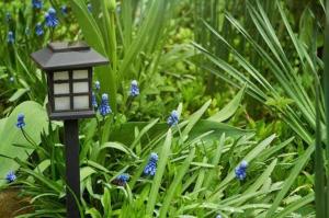 a black lamp post in the middle of blue flowers at De Villione Guesthouses in Bultfontein