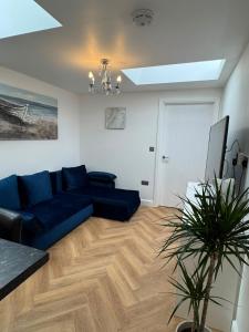a living room with a blue couch and a tv at Modern peaceful property Breakfast included in Blean