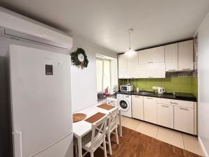 a kitchen with white cabinets and a table with chairs at Kosenko apartments in Zhytomyr
