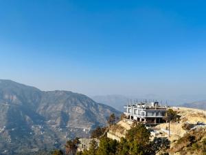 a house on top of a hill with mountains in the background at Naman Eco Resort in Solan +26 photos