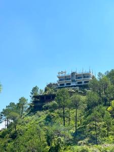 a building on top of a hill with trees at Naman Eco Resort in Solan