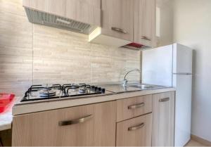 a kitchen with a stove and a white refrigerator at Villa Florence apartment con parcheggio in Torre Lapillo +26 photos