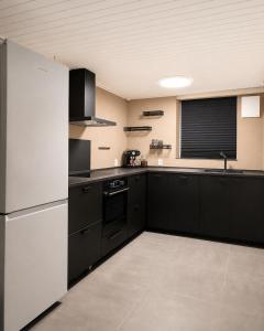 a kitchen with black cabinets and a white refrigerator at Quiet and charming studio apartment in Vejle