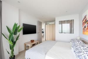 a white bedroom with a bed and a tv at Mountain and Sea view apartment in Nathon Bay +4 photos