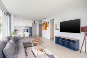 a living room with a couch and a tv on a wall at Mountain and Sea view apartment in Nathon Bay