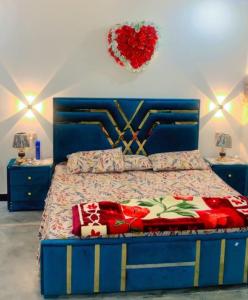 a bedroom with a blue bed with a heart decoration on the wall at The Skyline Cottage in Nathia Gali