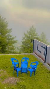 four blue chairs sitting in the grass next to a building at The Skyline Cottage in Nathia Gali