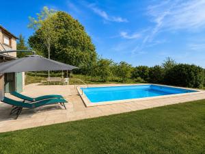 a swimming pool with a chair and an umbrella at Le Nid du Viaur in Pampelonne