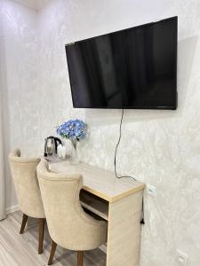 a desk with two chairs and a television on a wall at Comfort Hotel in Türkistan +6 photos