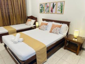 two beds in a room with two tables at JORA Studio Apartment 1-C in Dagupan