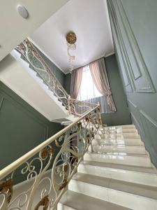 a staircase with white and gold railings and a window at Comfort Hotel in Türkistan