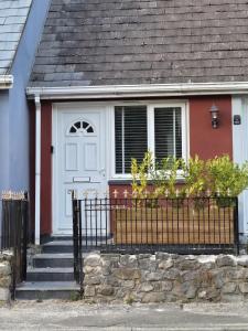 a house with a white door and a stone fence at Cosy Moat House Cottage #2 in Pembroke