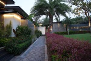 a walkway in front of a building with a palm tree at HF Pool Resorto in Chennai
