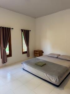 a bedroom with a large bed and two windows at JHOB Surf Stay in Maluk