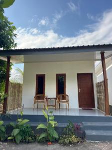a small house with two chairs on the porch at JHOB Surf Stay in Maluk