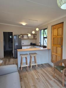 a kitchen with a counter and two stools in a kitchen at Beach cottage in Gonubie Park