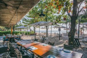a long wooden table and chairs on the beach at MARINA SEASIDE BEACH BOUTIQUE Phu Quoc - Infinity Pools - PREMIUM SOLAR ENERGY in Phú Quốc