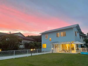 a house with a lawn in front of a sunset at 静岡 伊豆高原 ペットと泊まれるプライベートヴィラ Tous les doudouトゥレ ドゥドゥ in Ito