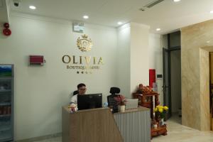 a man sitting at a desk in a hotel lobby at Olivia Hotel in Ấp Thành