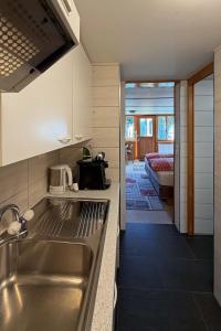 a kitchen with a stainless steel sink and a living room at Studio bim Chalet bim Chilchli in Mürren