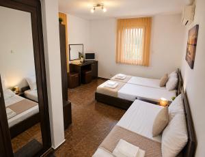 a hotel room with two beds and a mirror at Хотел Свети Димитър in Sozopol