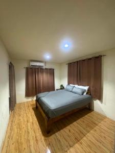 a bedroom with a bed in a room with wooden floors at Ezzy Air B&B in Salelologa