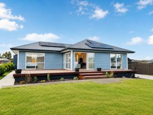 a blue house with a porch and a lawn at The Burnby in Te Anau